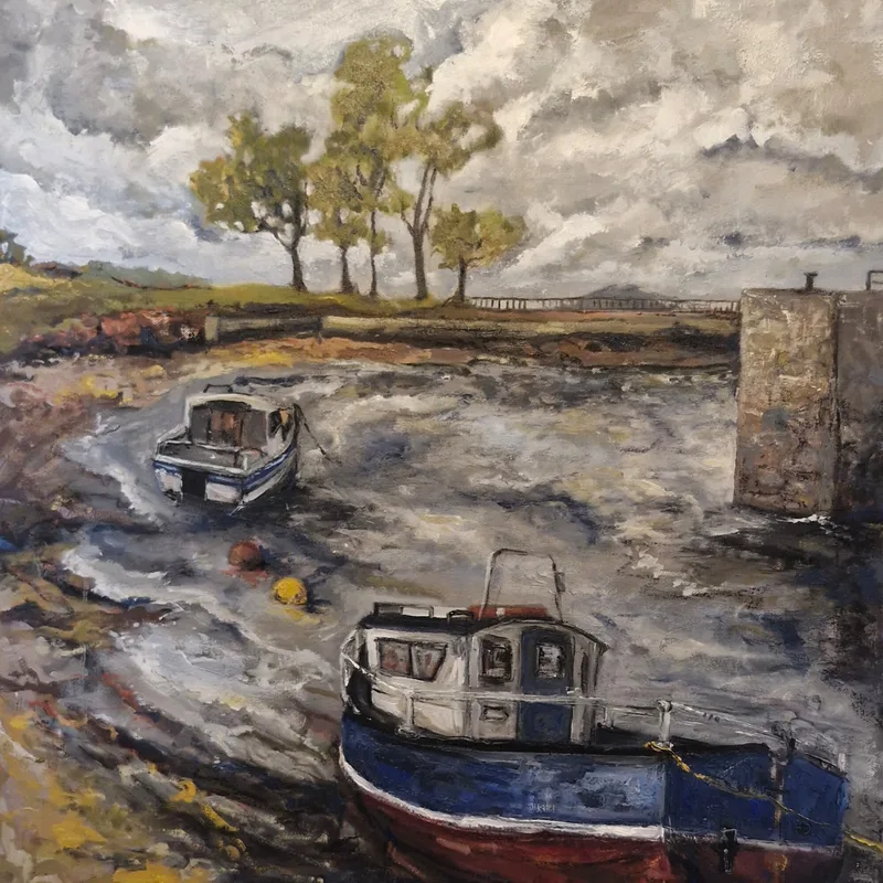 Two fishing boats, one with a blue hull, beached on wet sand in Cockenzie harbour at low tide, a stone harbour wall and a row of trees under a grey sky