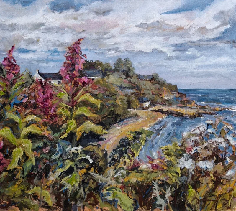 Pink willowherb and green foliage on a clifftop, a path leading round the bay towards cottages and the sea under a pale cloudy sky