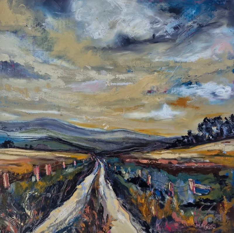 A pale track running straight up through moorland towards distant blue hills, under a wide sky of swirling grey and yellow cloud