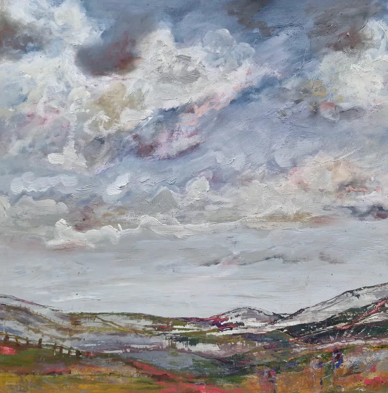 A wide valley with snow touched hills beneath a large sky of white and grey cloud