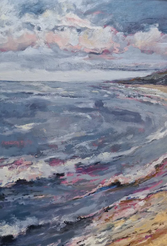Grey blue waves rolling in towards a pink tinged shoreline under a soft pink and grey sky
