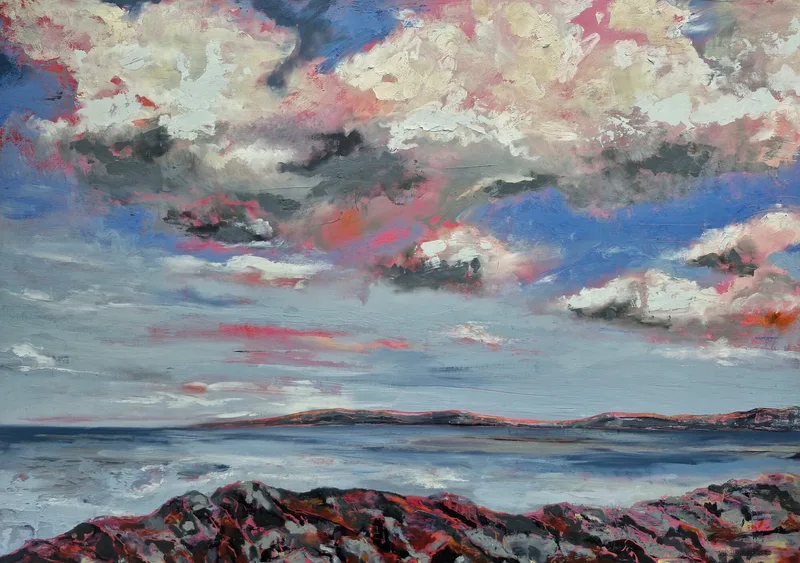 Billowing white and pink clouds over a calm grey estuary, with dark red rocks along the shore