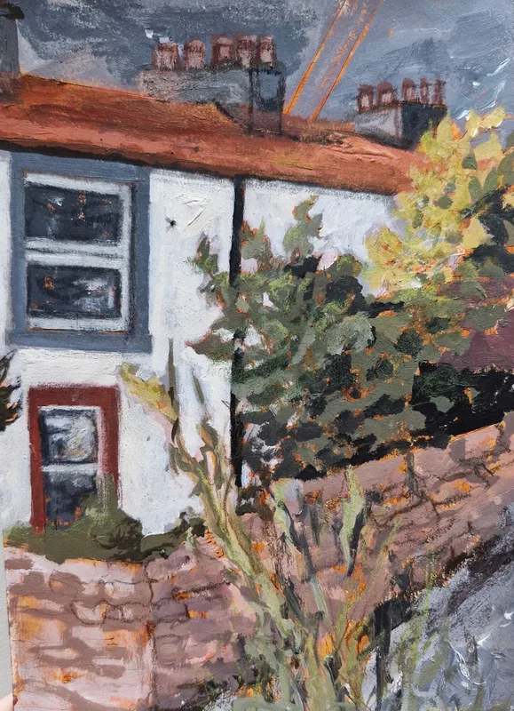 A white cottage with a red roof and chimneys behind a stone wall and a yellow green bush